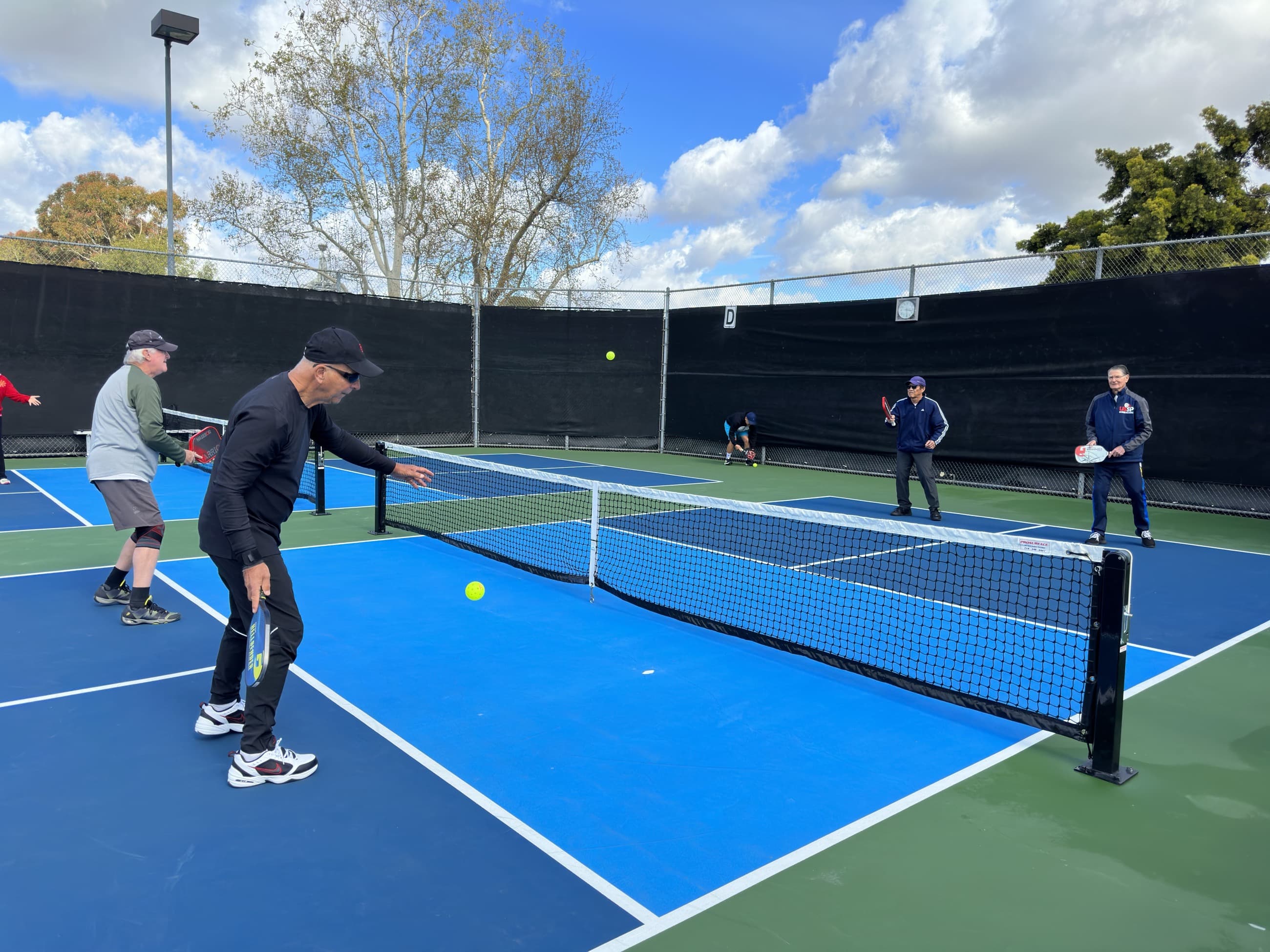 Doubles partners cover a vivid blue court in a lively rally.